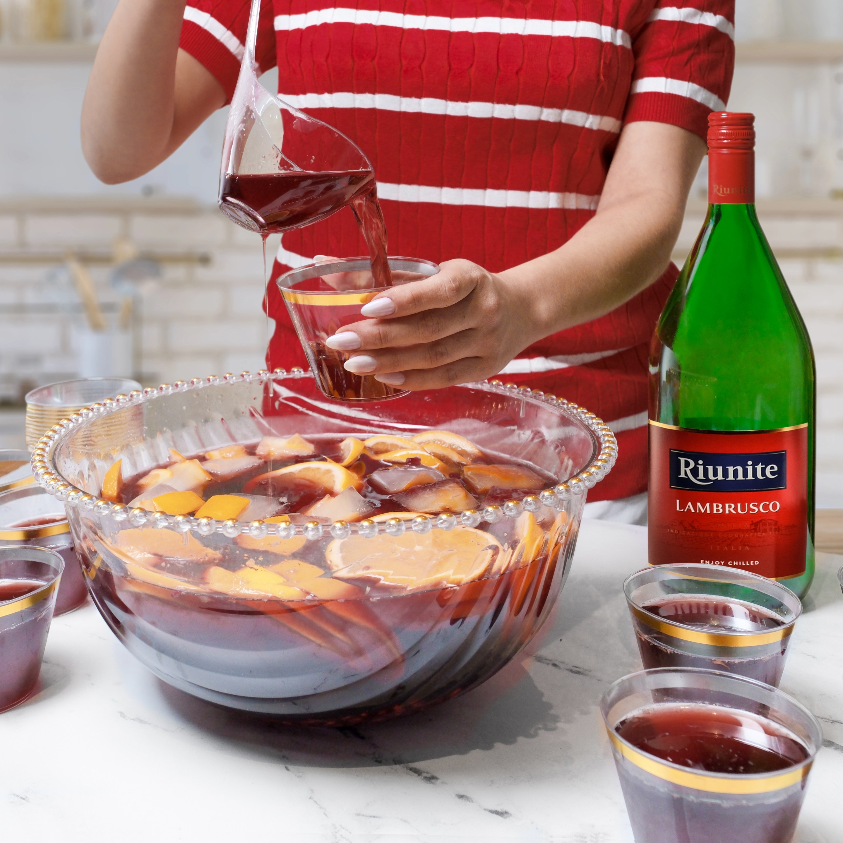 Lambrusco Punch made with chilled Riunite Lambrusco, pomegranate juice, citrus, and frozen fruit cubes brings a festive Italian twist to Super Bowl Sunday entertaining.