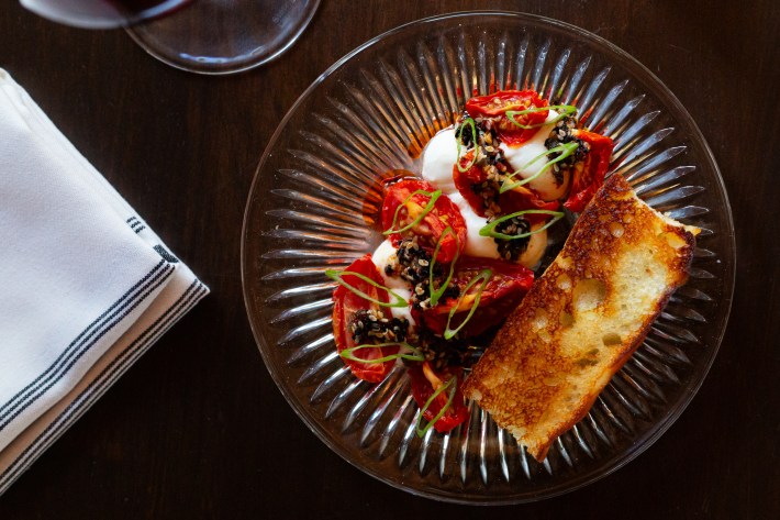 Stracciatella cheese with tomatoes and toasted sourdough focaccia on a glass plate. Courtesy of Poeta