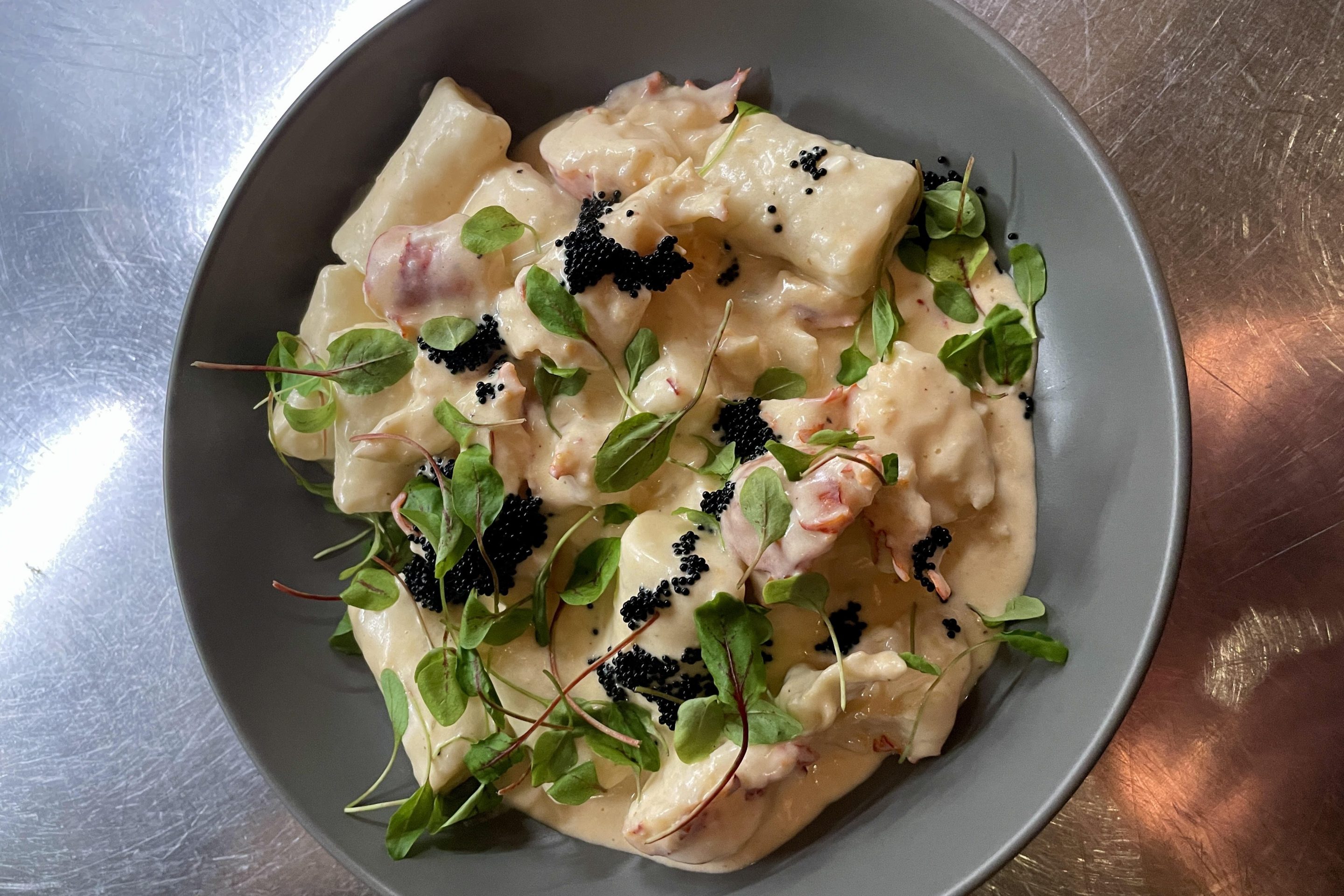 Ricotta gnocchi with lobster cream, micro sorrel, and black tobiko. Courtesy of Cipollini.