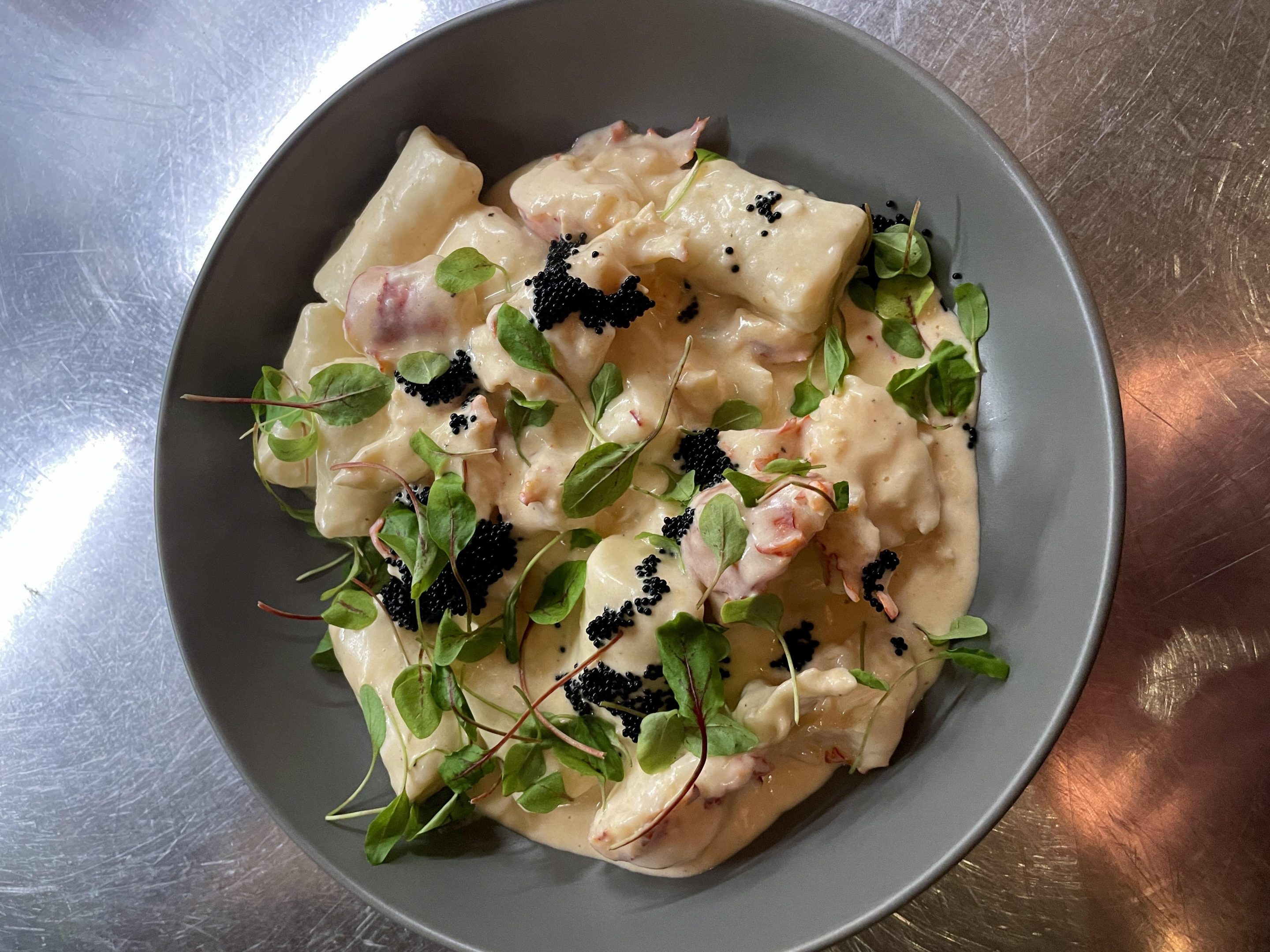 Ricotta gnocchi with lobster cream, micro sorrel, and black tobiko. Courtesy of Cipollini.