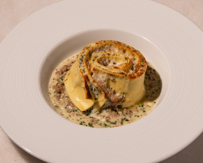 Rotolo Bianco pasta layered with white Bolognese, kale, and ricotta in a creamy sauce.
