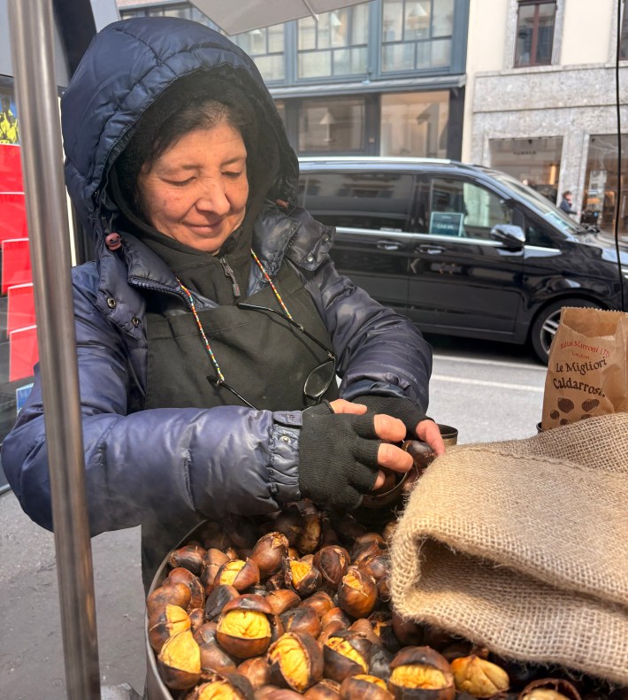 Woman roasting Italian marroni chestnuts on Milan street