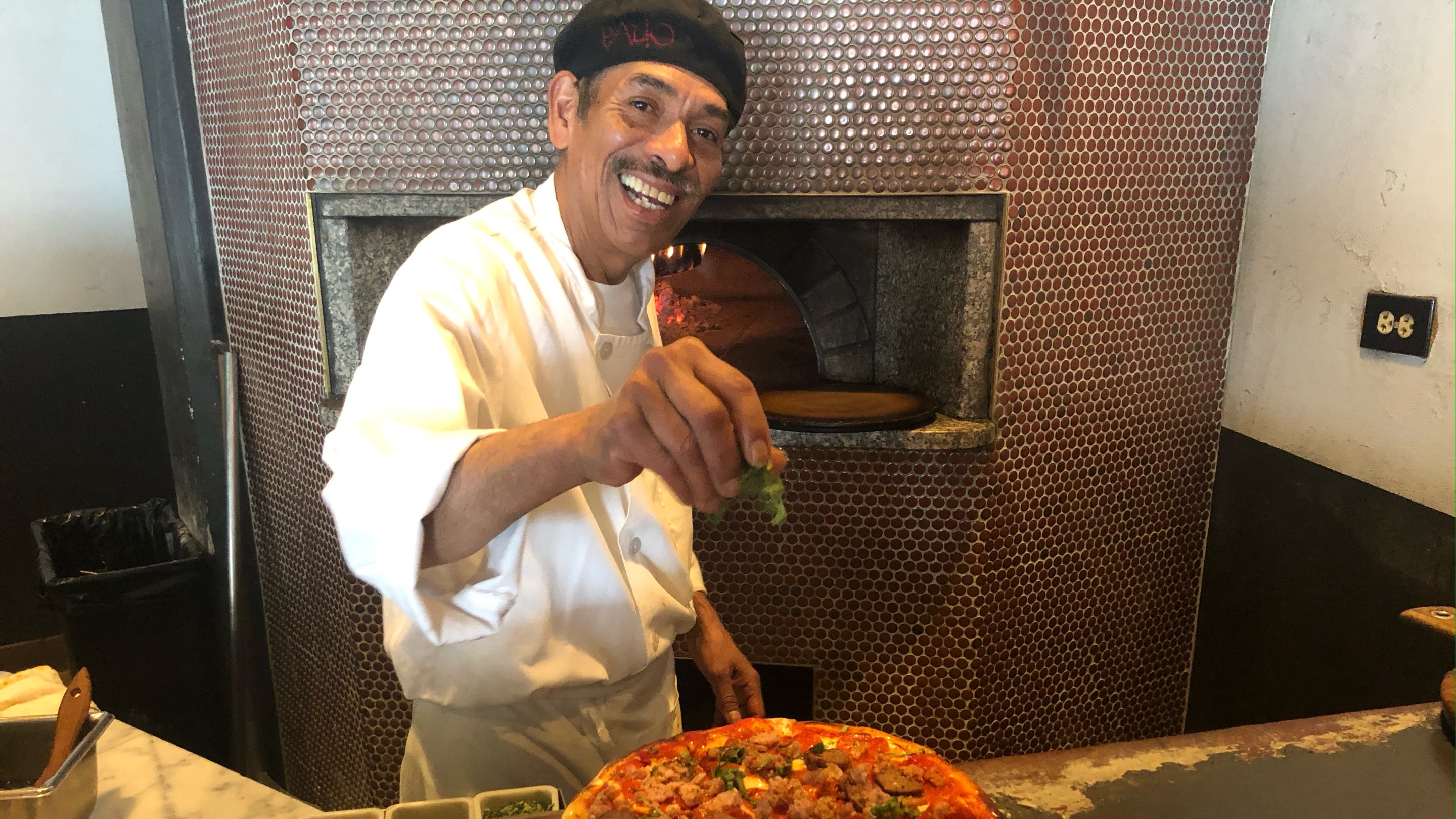 Pizzaiolo Donaldo finishing a pizza at Palio's