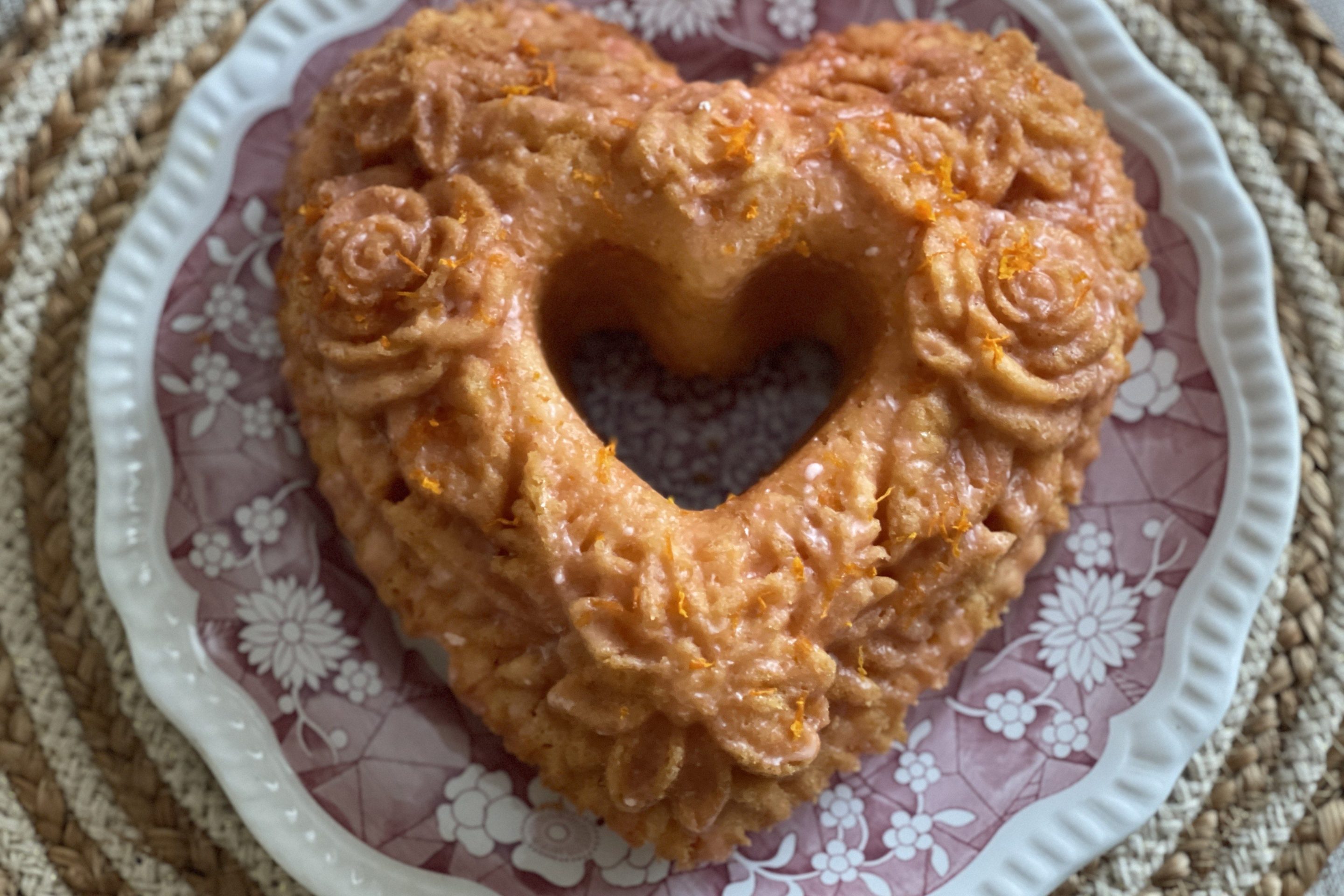Golden citrus Aperol Spritz cake topped with fresh berries and powdered sugar, served on a white plate.
