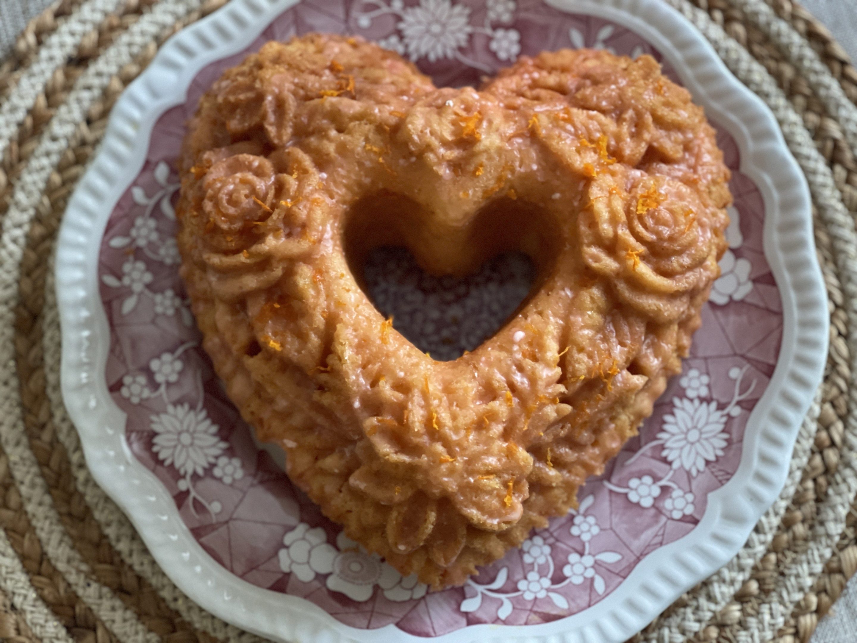 Golden citrus Aperol Spritz cake topped with fresh berries and powdered sugar, served on a white plate.