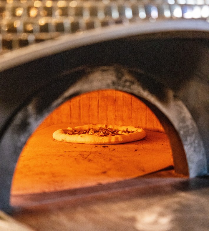 Pizza cooking inside the wood fired oven at Francesco Martucci Miami.