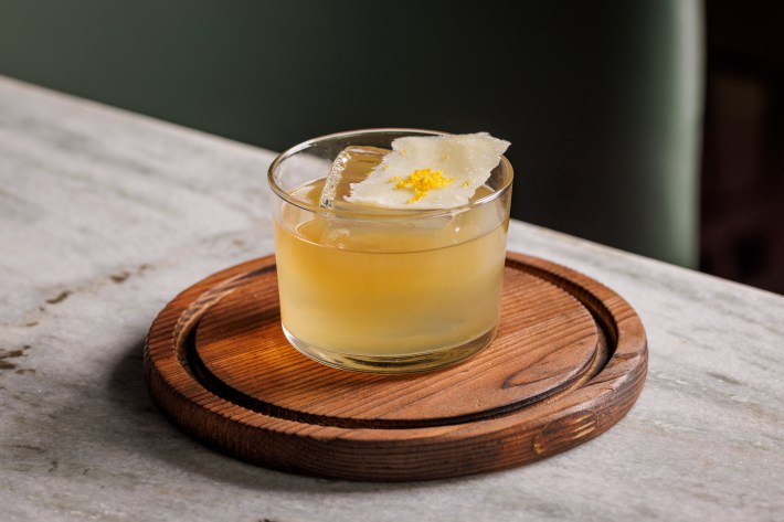 The Parmigiano Old Fashioned at Urban Italia, served on a wooden, round board on a marble table.