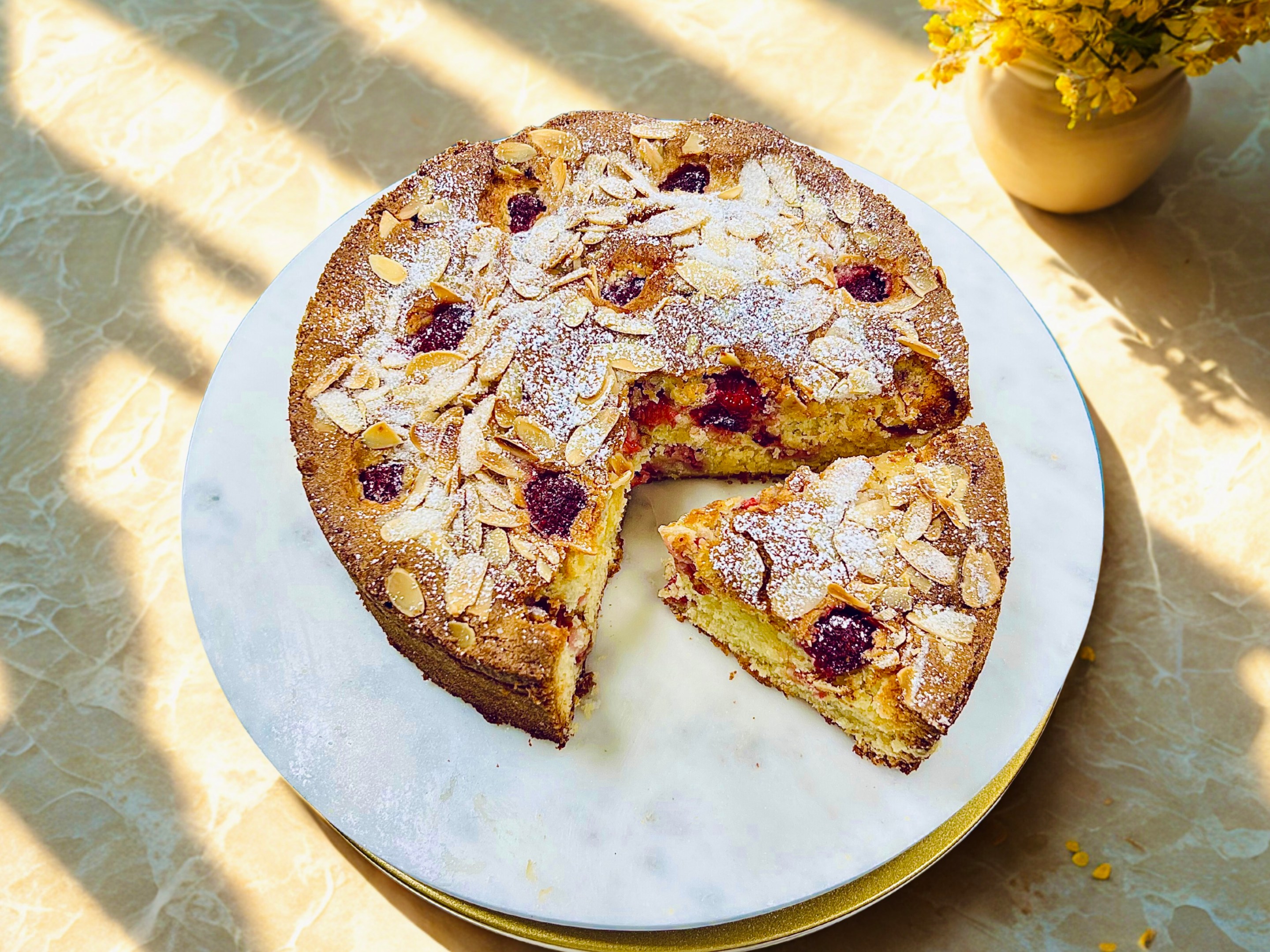 Gluten free amaretto raspberry cake on a white round platter