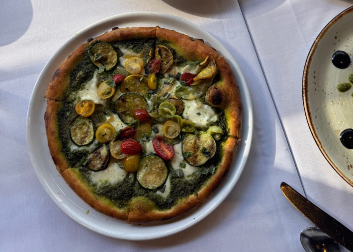 A seasonal vegetable pizza at Palio, on a white plate on a white tablecloth.