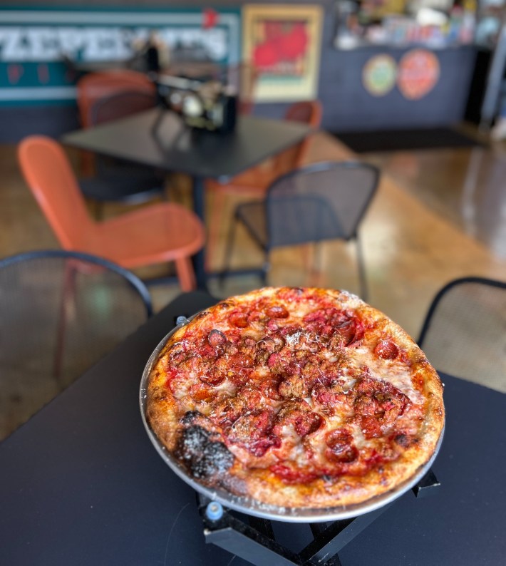 New York–style pizza with pepperoni and sausage on metal pizza stand