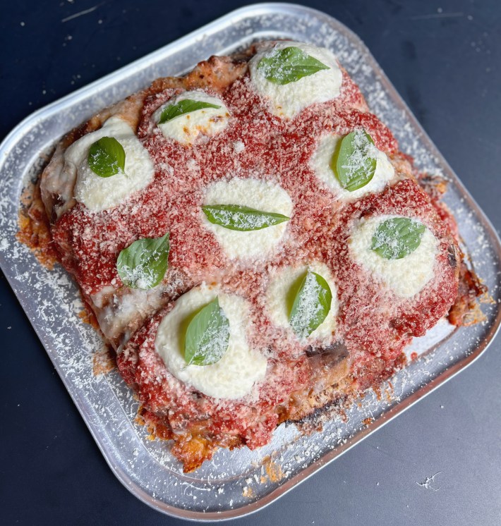 Sicilian square pizza topped with mozzarella, tomato sauce, and basil