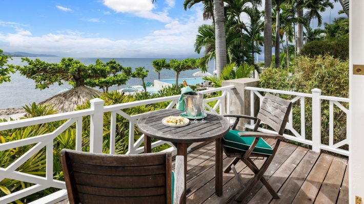 Oceanfront balcony with table and chairs overlooking the sea at Round Hill Hotels and Villas in Jamaica.
