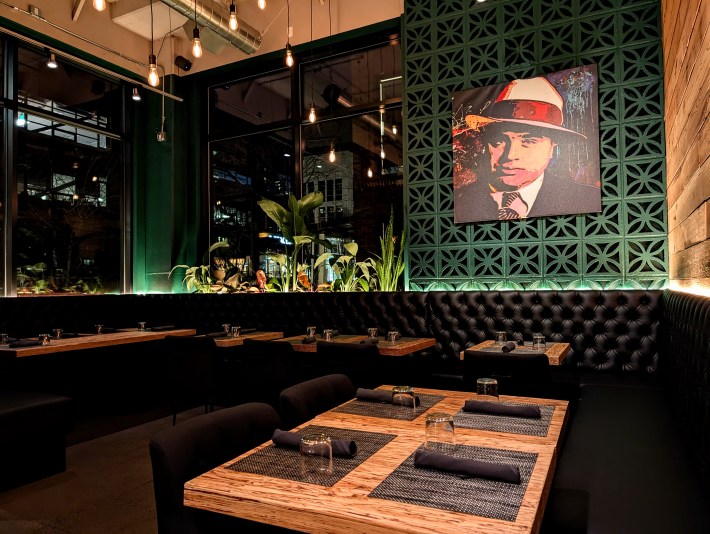Interior of Bistecca restaurant in Portland featuring green tiled walls, leather banquettes, and wood dining tables.