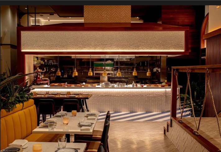 Open kitchen and dining room at Costa Charleston inside The Jasper with polished wood, brass accents, and coastal-inspired design.