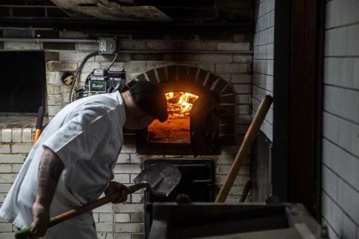 Chef Nino Coniglio tending the coal oven at Lucky Charlie in Bushwick.