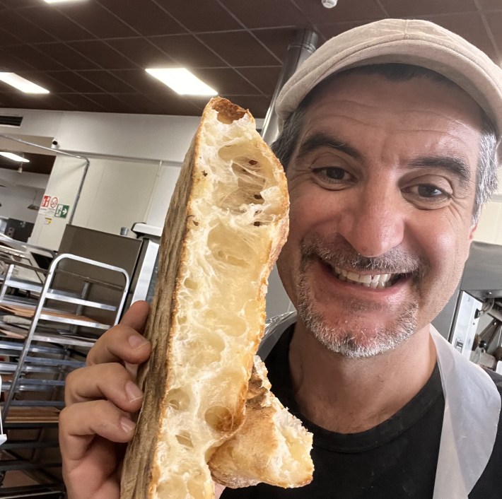 Chef Michele holding bread in the kitchen, smiling
