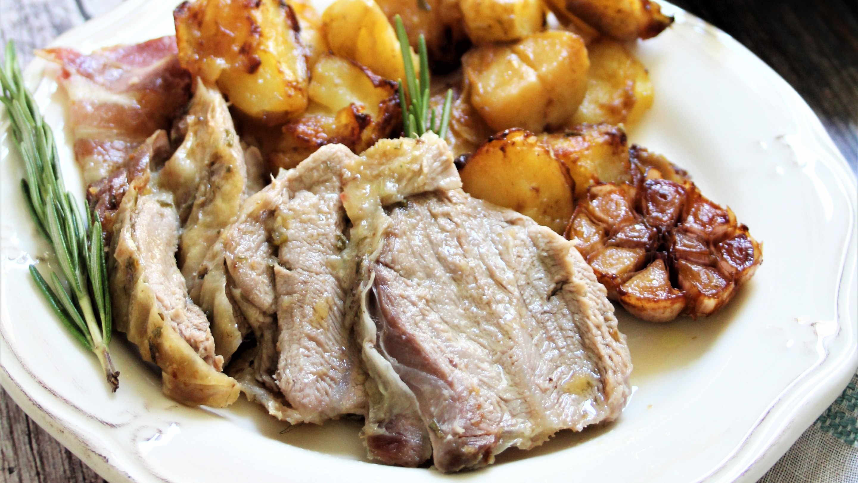 plated roast lamb with potatoes garlic and rosemary