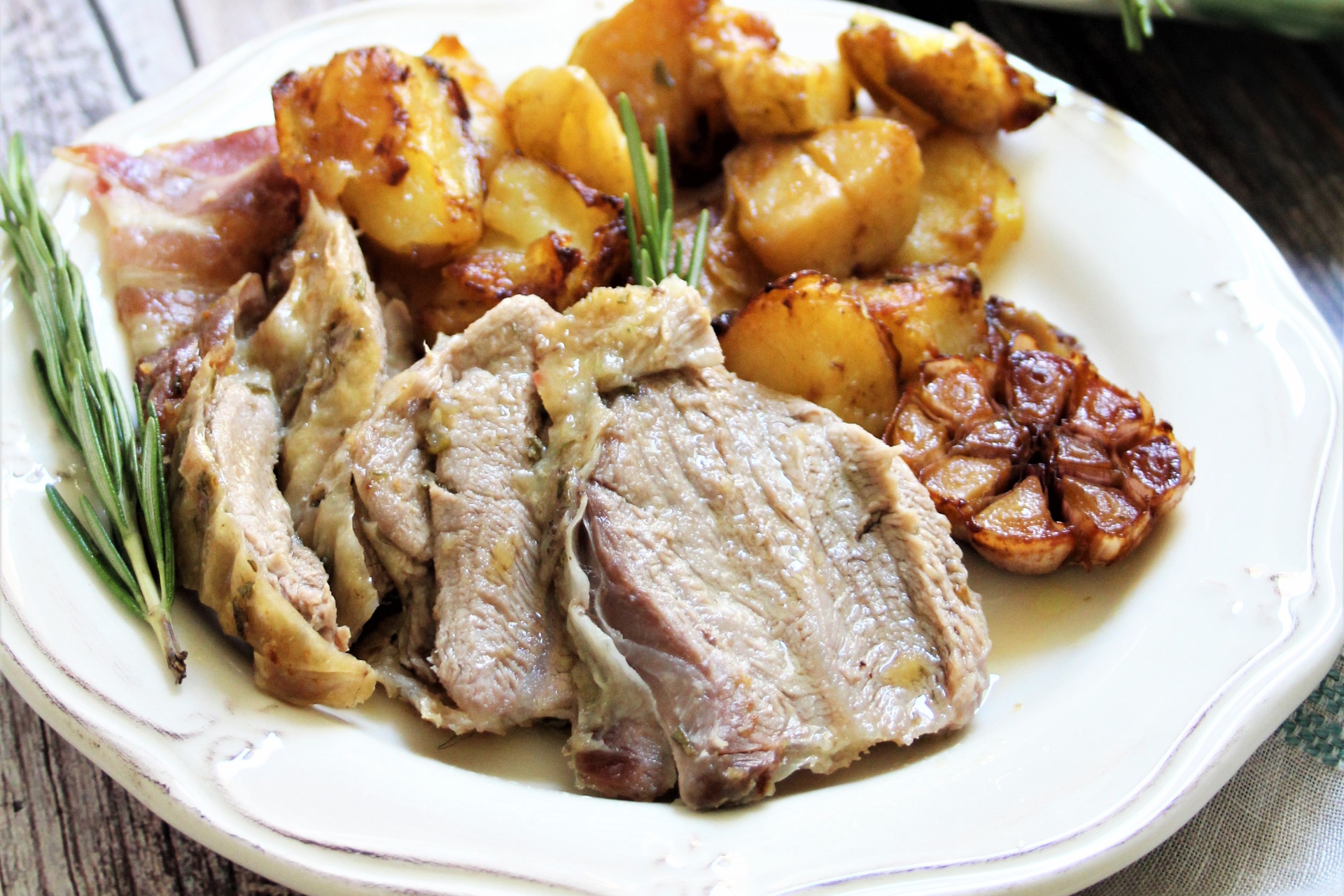 plated roast lamb with potatoes garlic and rosemary