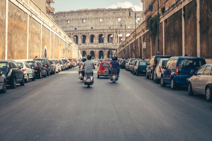 Vespa riders driving through Rome city streets traffic
