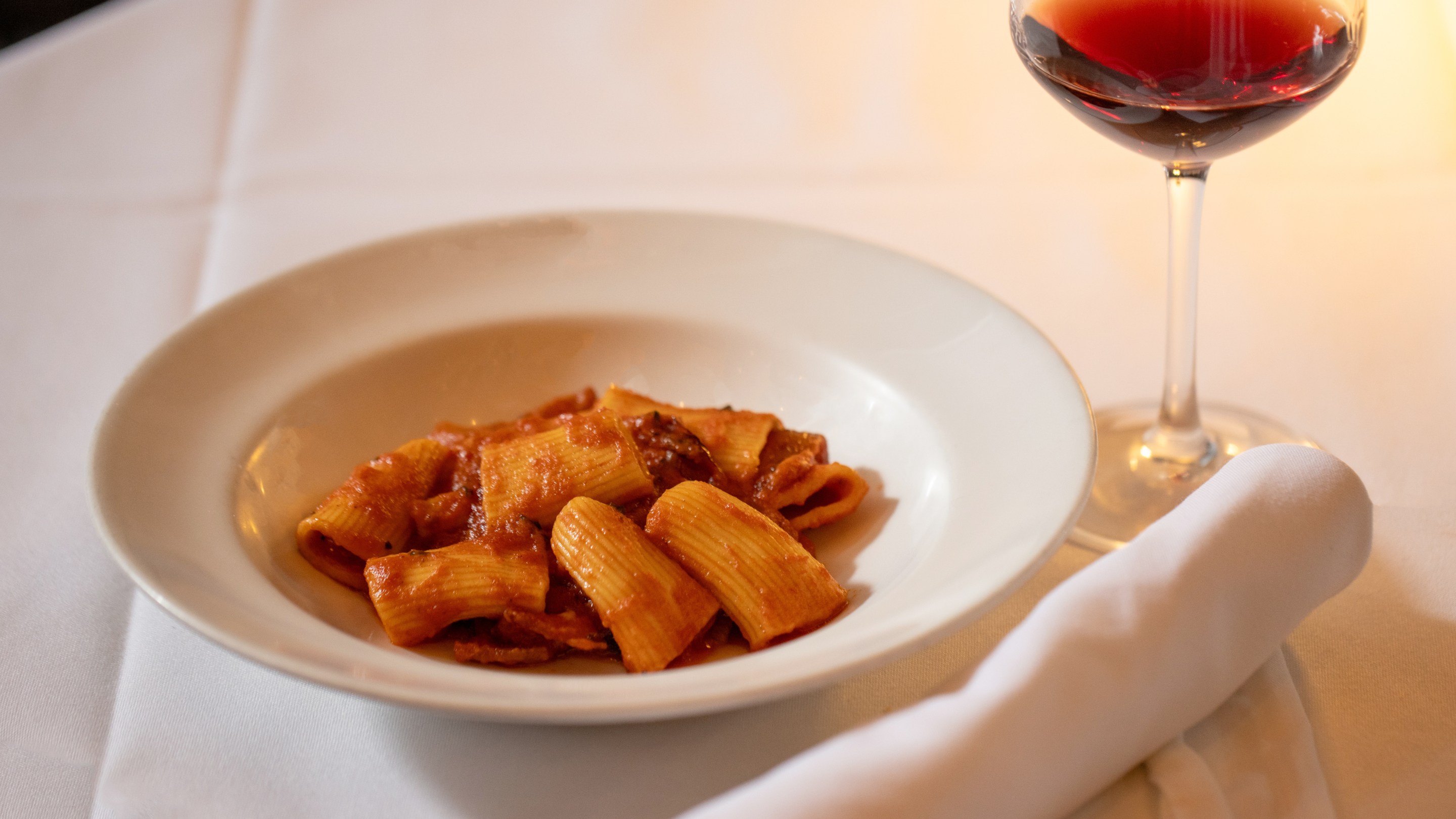 Rigatoni Amatriciana paired with Roero DOCG red wine at dinner, part of Sip and Savor: Pairing European Wines and Deli Meats Campaign Co-funded by the European Union.