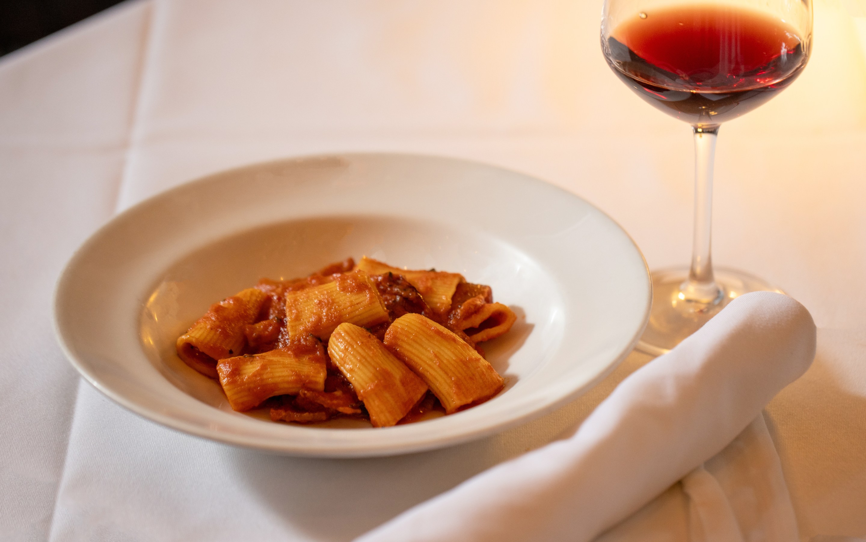 Rigatoni Amatriciana paired with Roero DOCG red wine at dinner, part of Sip and Savor: Pairing European Wines and Deli Meats Campaign Co-funded by the European Union.