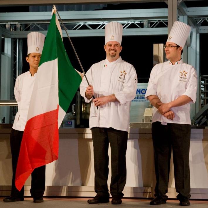 Italian pastry chef Andrea Zanin holding Italian flag at competition