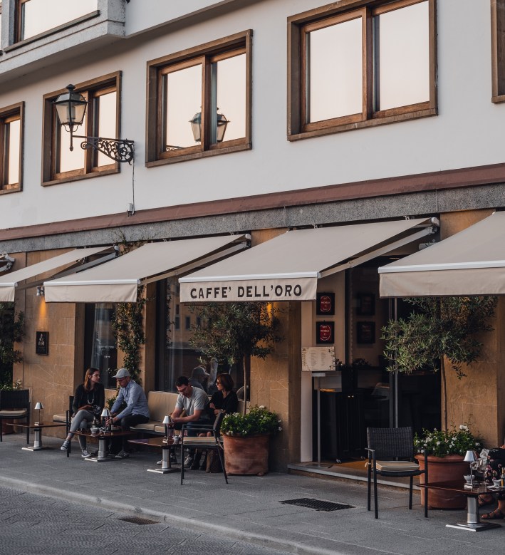 Exterior of Caffè dell’Oro Florence with awning and outdoor seating along the river