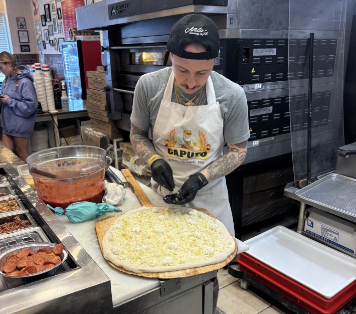 Pizzaiolo adding toppings to a pizza in a restaurant kitchen