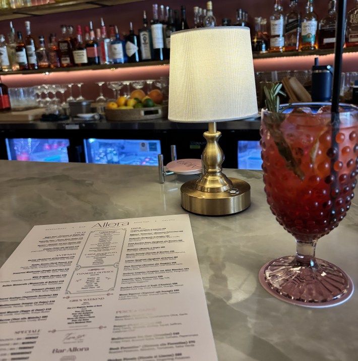 Cocktail on bar with menu and bottles behind