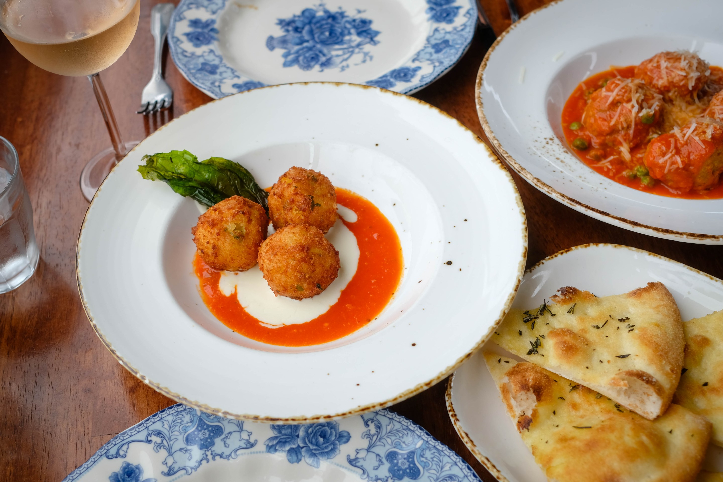 Arancini with sauces, meatballs in tomato sauce, and focaccia on a table.