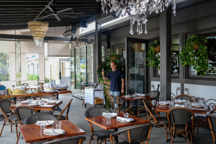 Outdoor dining area at Osteria Molo with wooden tables, chairs, and chandeliers.