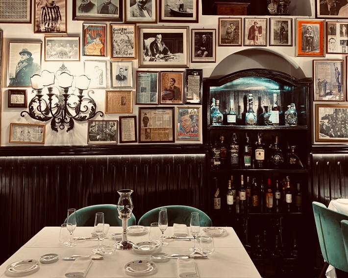Restaurant booth with bottles of alcohol and vintage photos on the wall in Sorrento.