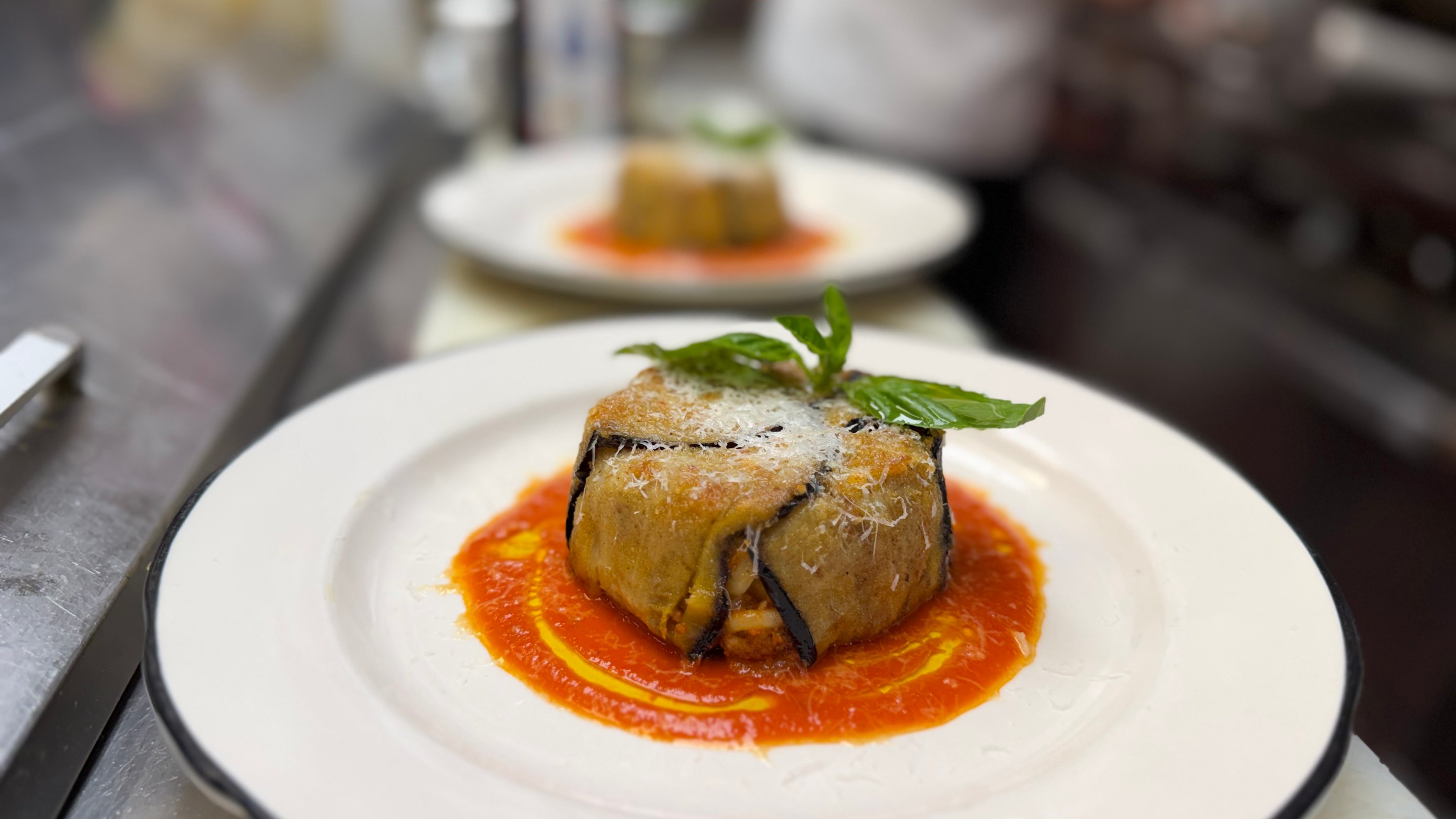 Timballo di anelletti plated with tomato sauce and basil garnish