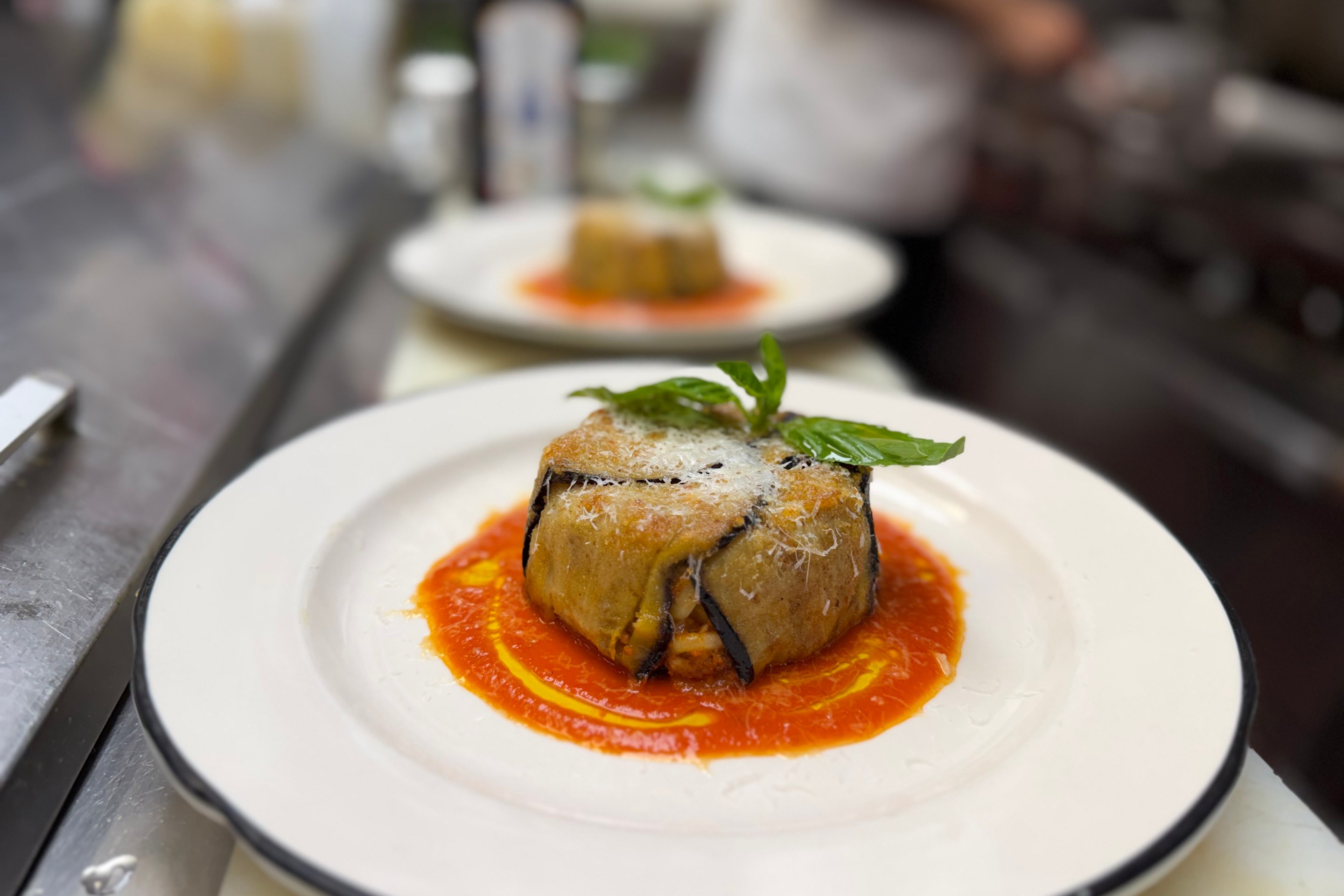 Timballo di anelletti plated with tomato sauce and basil garnish