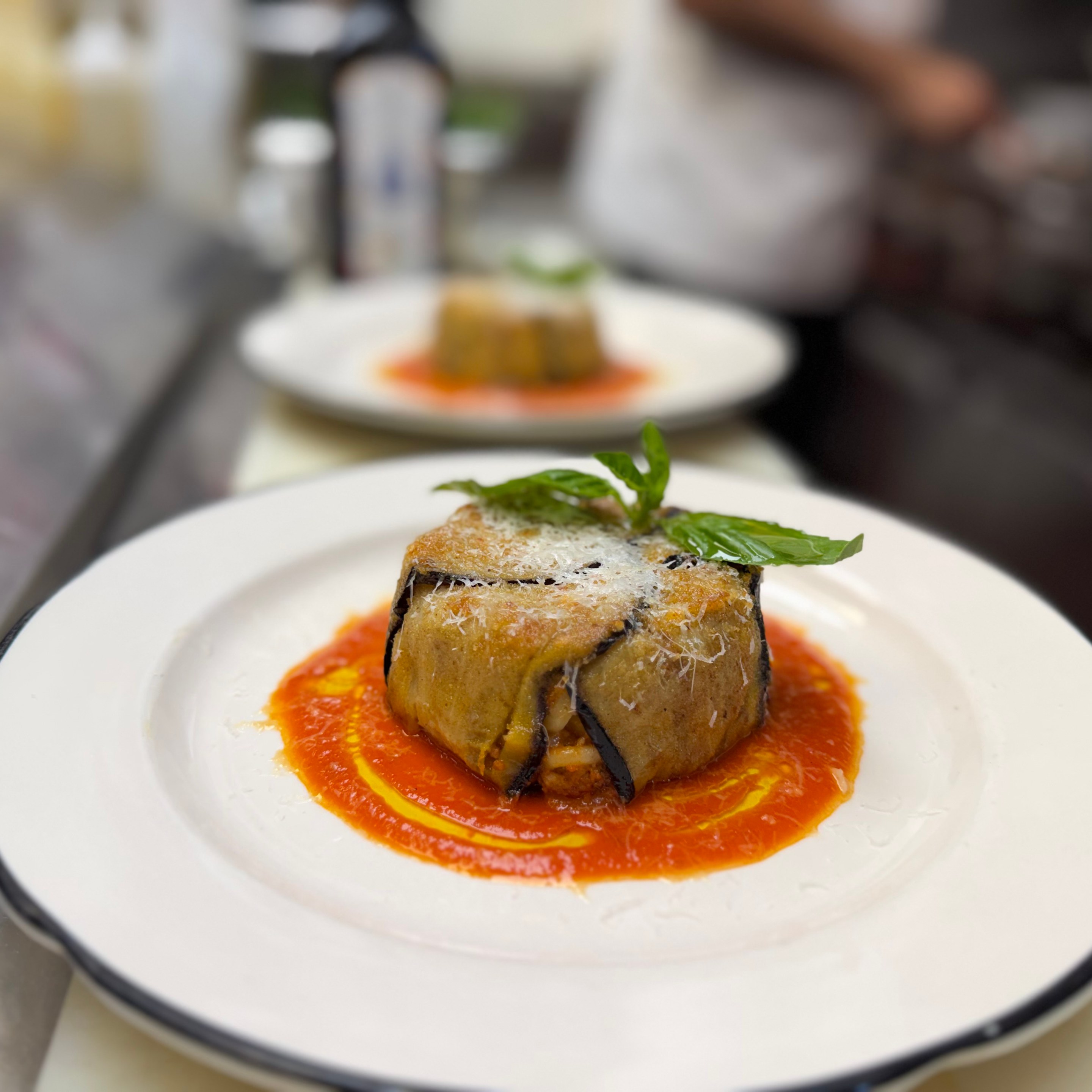 Timballo di anelletti plated with tomato sauce and basil garnish