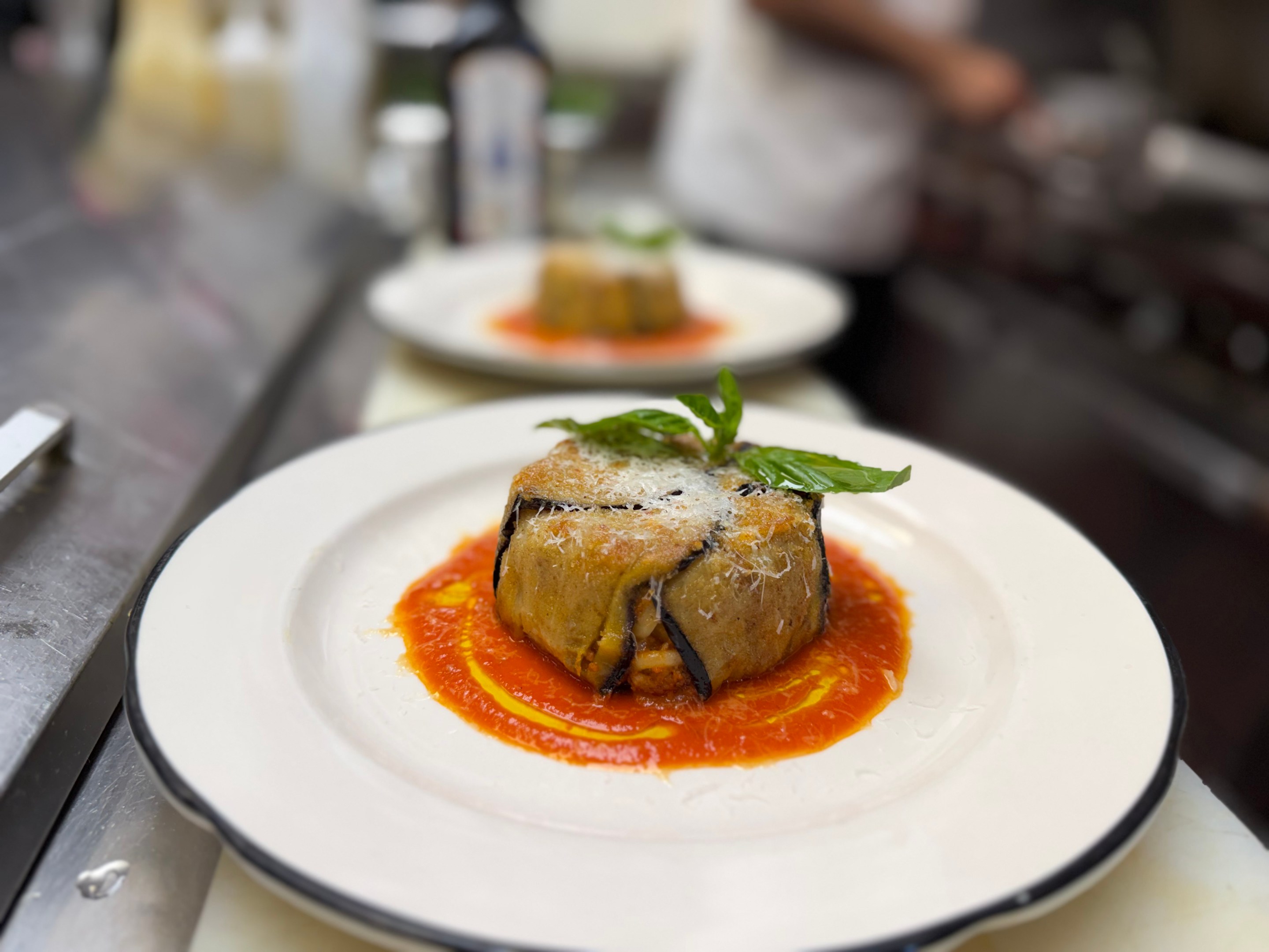 Timballo di anelletti plated with tomato sauce and basil garnish