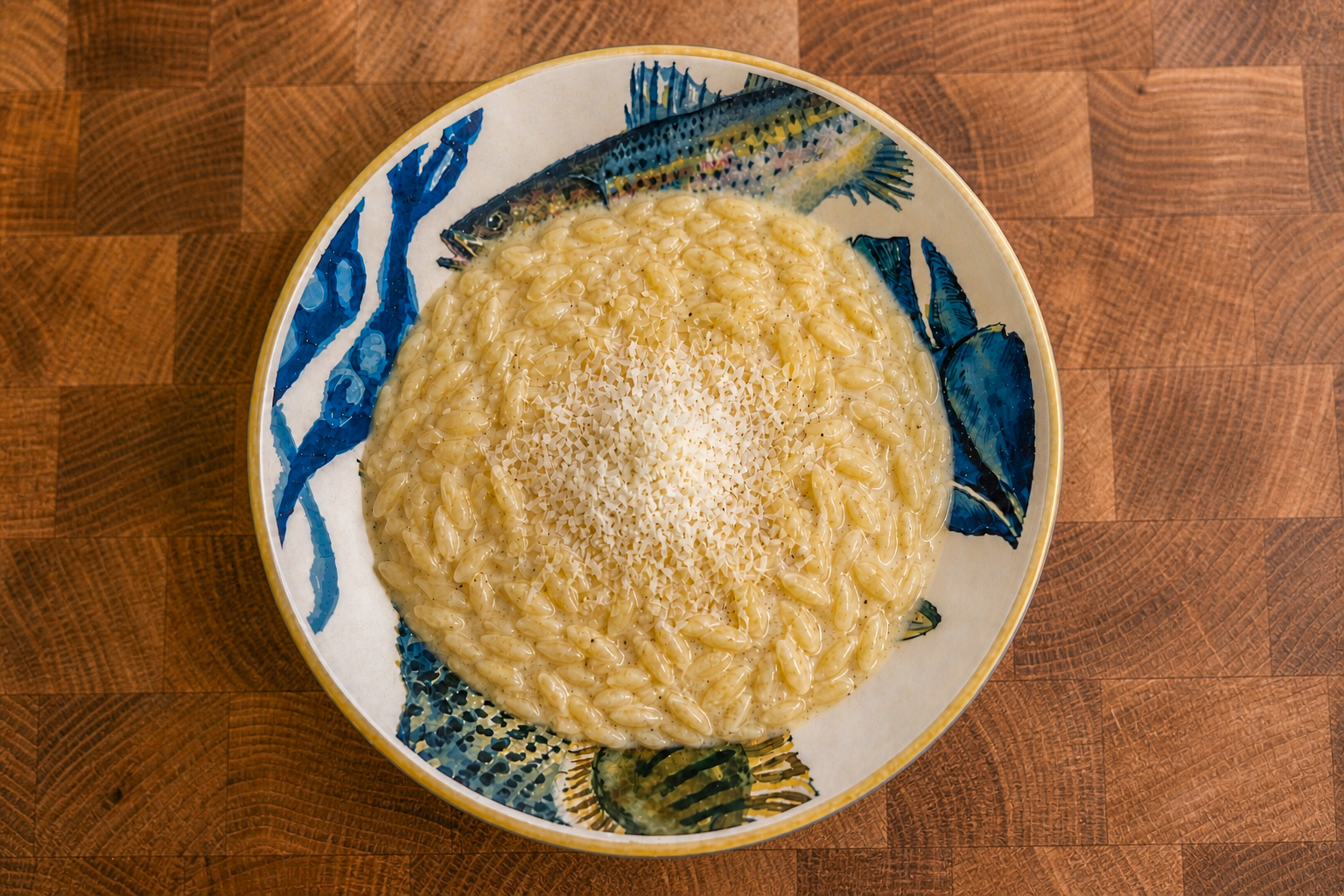Creamy pastina al formaggino with grated cheese in a patterned bowl