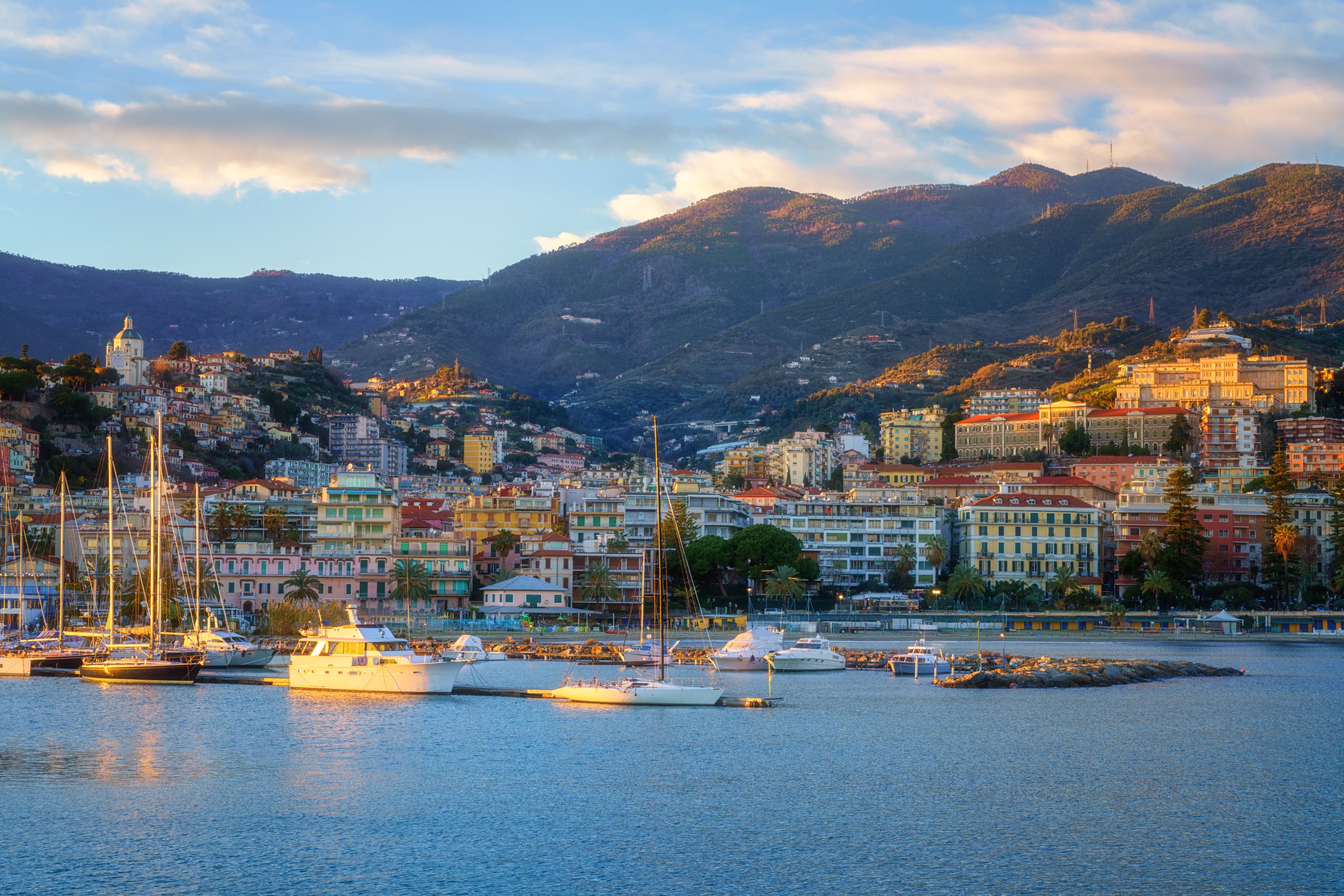 View of Sanremo on the Italian Riviera with boats and mountains at sunset