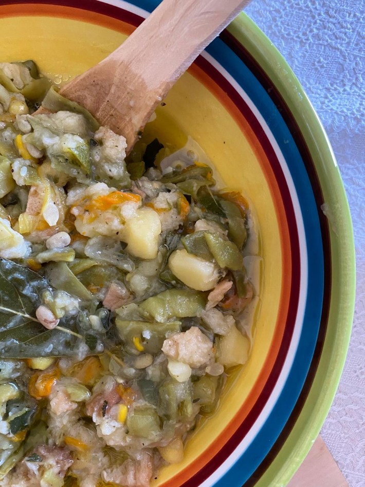 Traditional Arbëreshë soup in a colorful bowl with a wooden spoon.