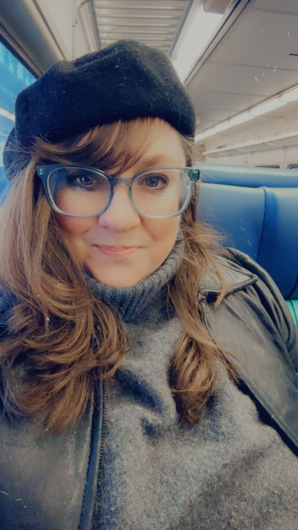 Writer Kristin Wolfe in a black hat with glasses.
