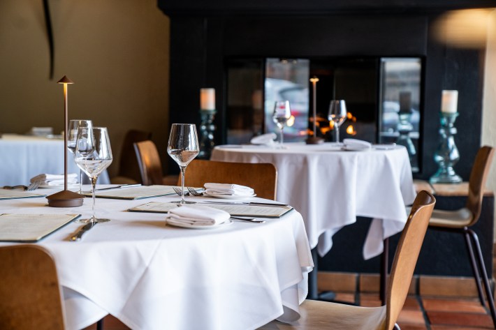 White tablecloth dining room at Barolo Grill in Denver with a fireplace and intimate seating.