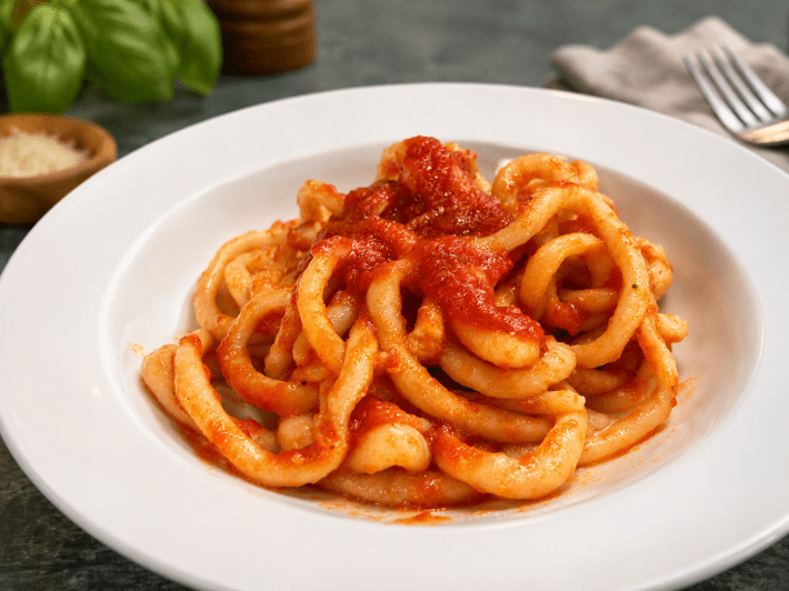 Homemade Tuscan pici pasta served with tomato sauce.