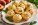 Homemade peach basil cheddar muffins arranged on a serving platter with fresh basil leaves and peaches.