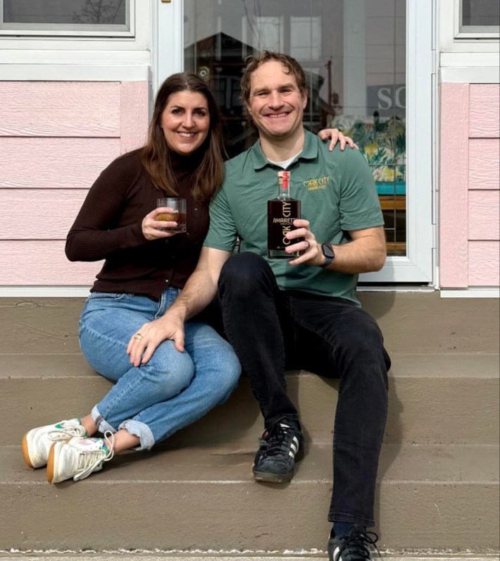 Anthony and Miranda Scalabrino holding a bottle of Oak City Amaretto