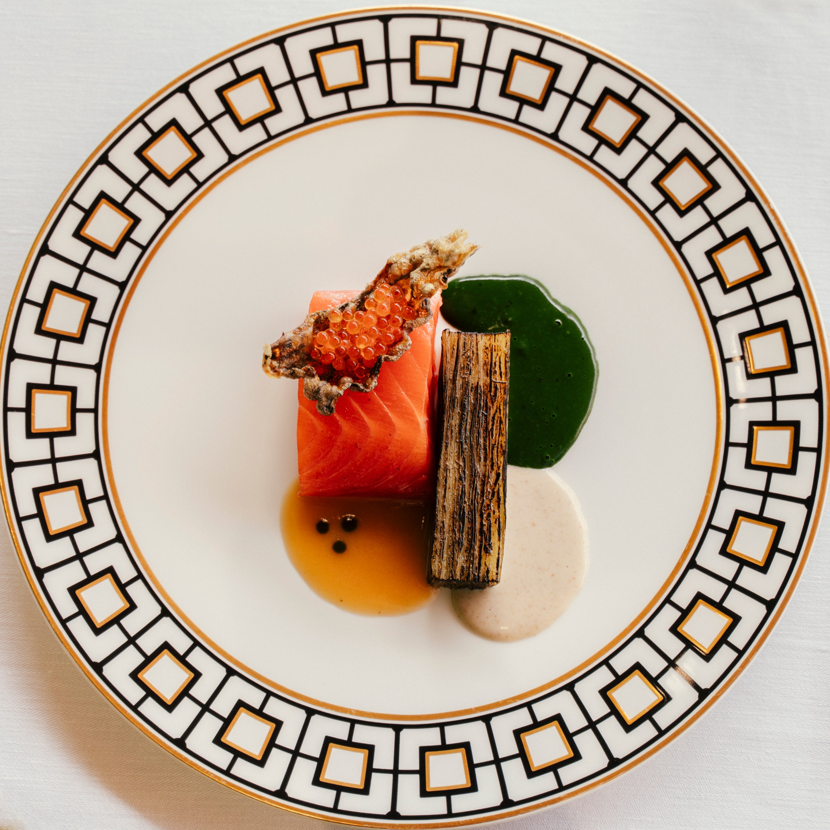 The Iced Trout: Salmon Trout, green apple and horseradish at Lido Palace on a white plate with gold and black square trim.