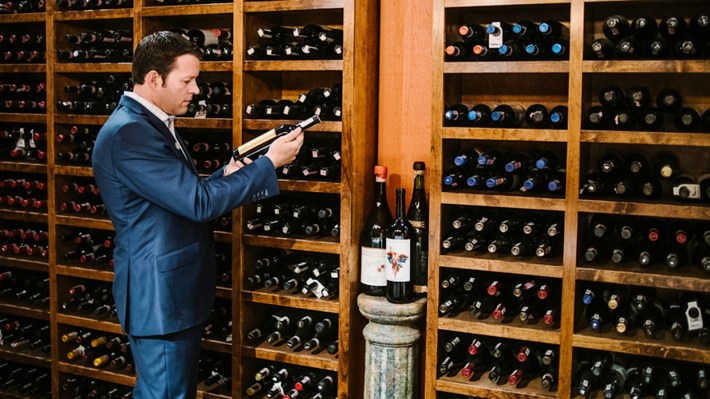 Ryan Fletter examining a bottle of wine in Barolo Grill’s extensive wine cellar in Denver.