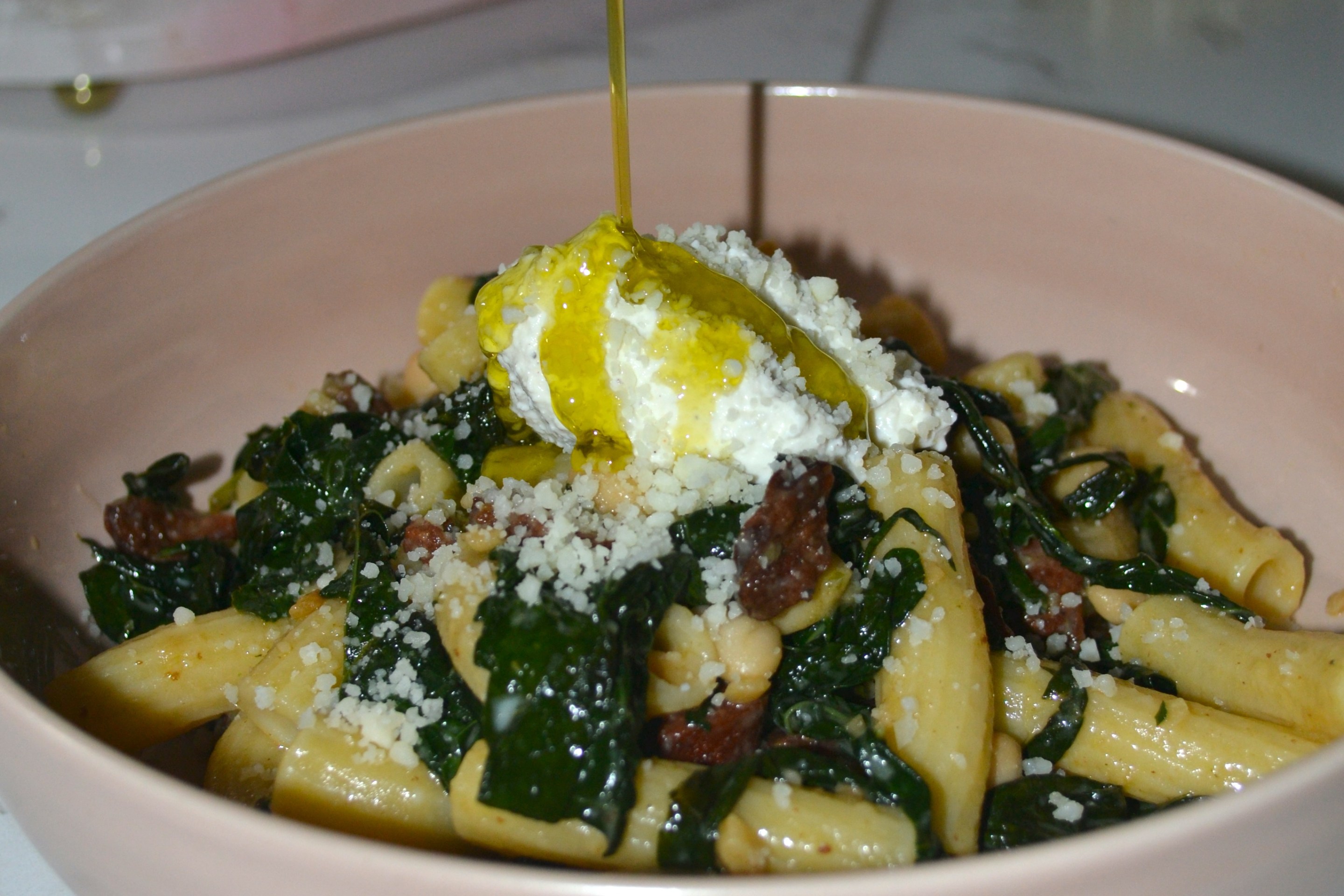 Bowl of rigatonini pasta with andouille sausage, Lacinato kale, cannellini beans, ricotta and grated Pecorino Romano.