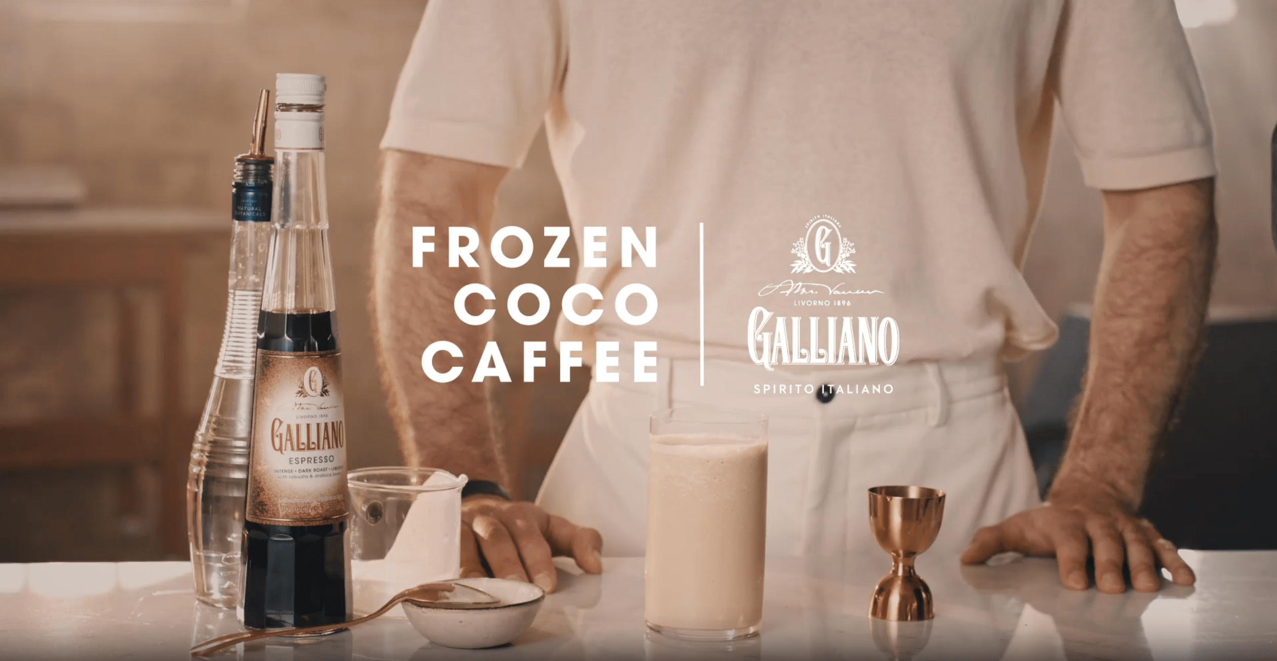 Frozen Coco Caffè espresso cocktail served in a tall glass beside a bottle of Galliano Espresso.