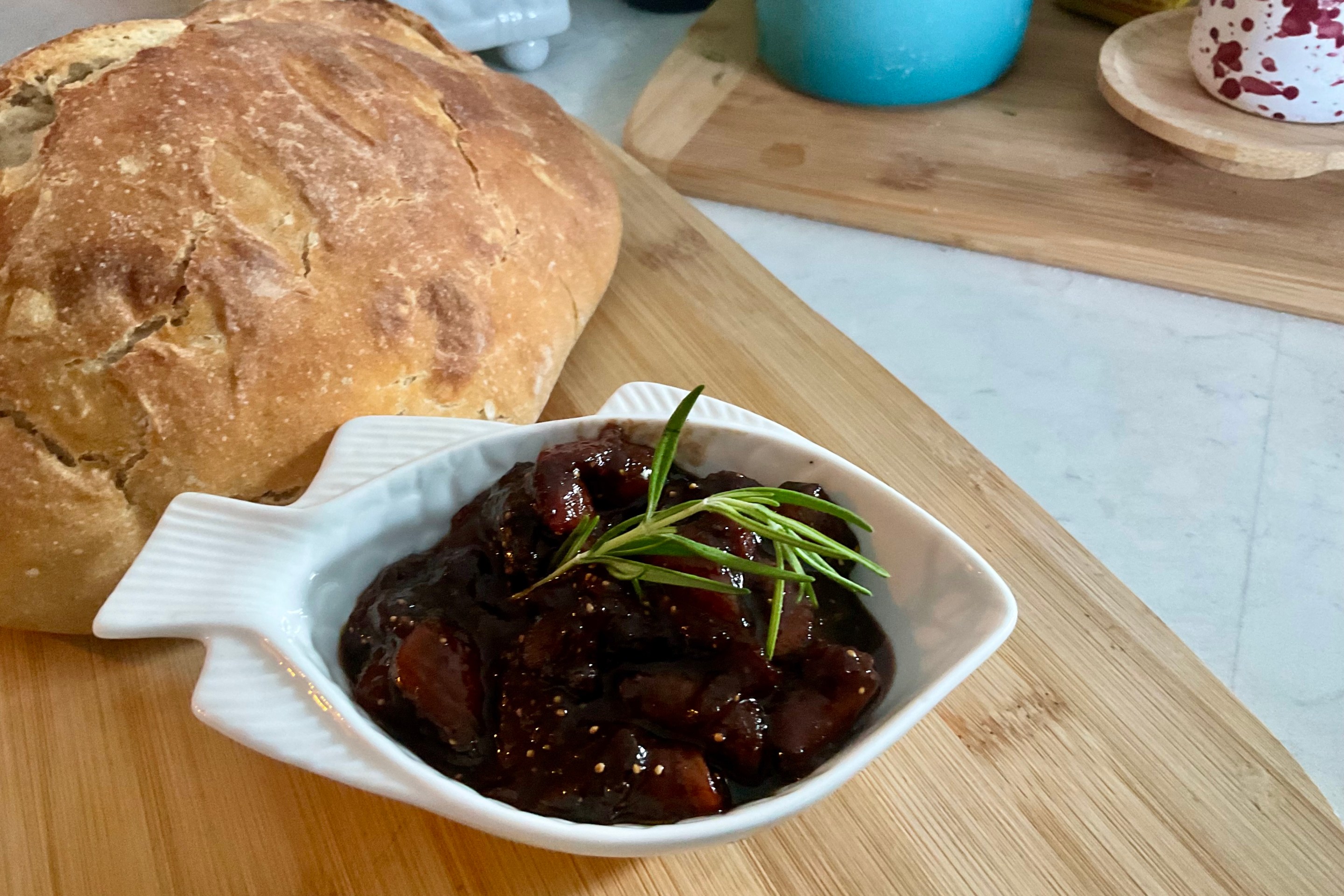 Bowl of homemade fig preserve with a loaf of rustic bread.