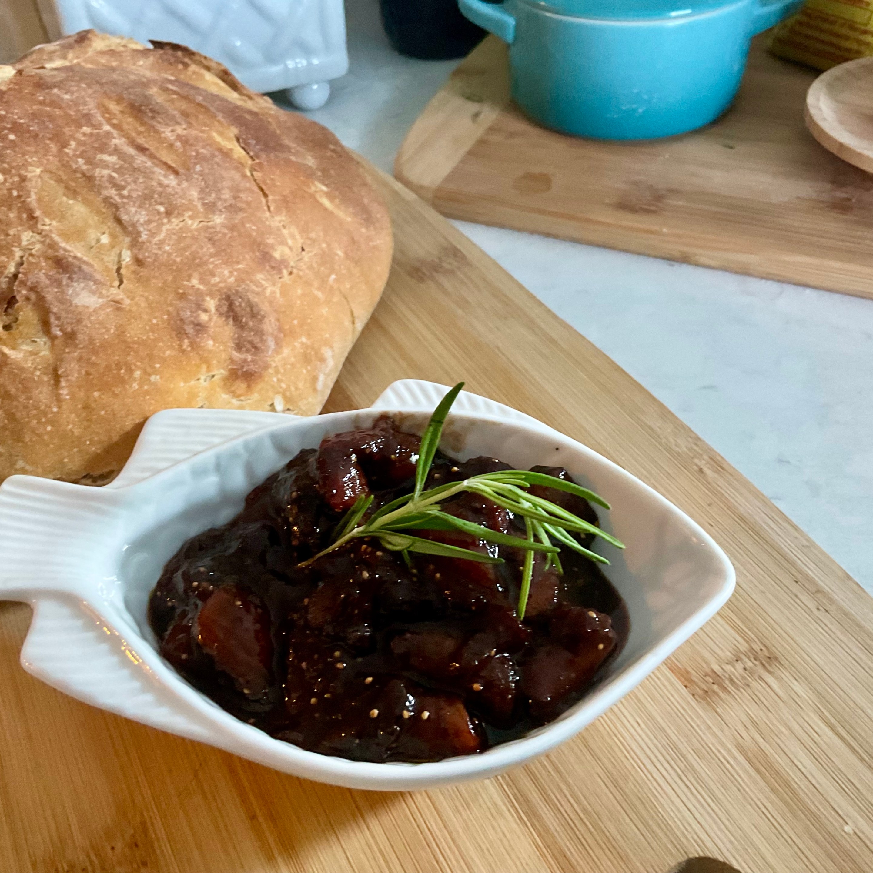 Bowl of homemade fig preserve with a loaf of rustic bread.